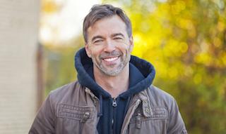 standing man smiling with bright smile I dental implants in moline il
