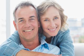 middle-aged couple facing forward smiling I restorative dentistry in moline il